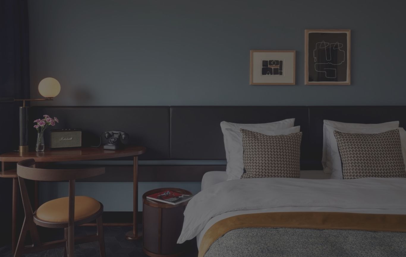 Hotellinteriör, sovrum med säng och skrivbord framför blå vägg